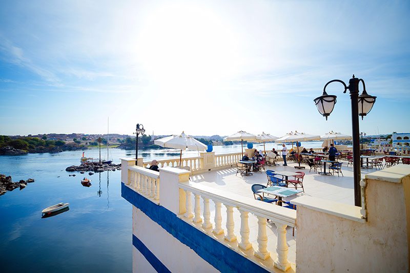 A blue and white terrace above the Nile at the Nubian village guesthouse, with tables set out under umbrellas